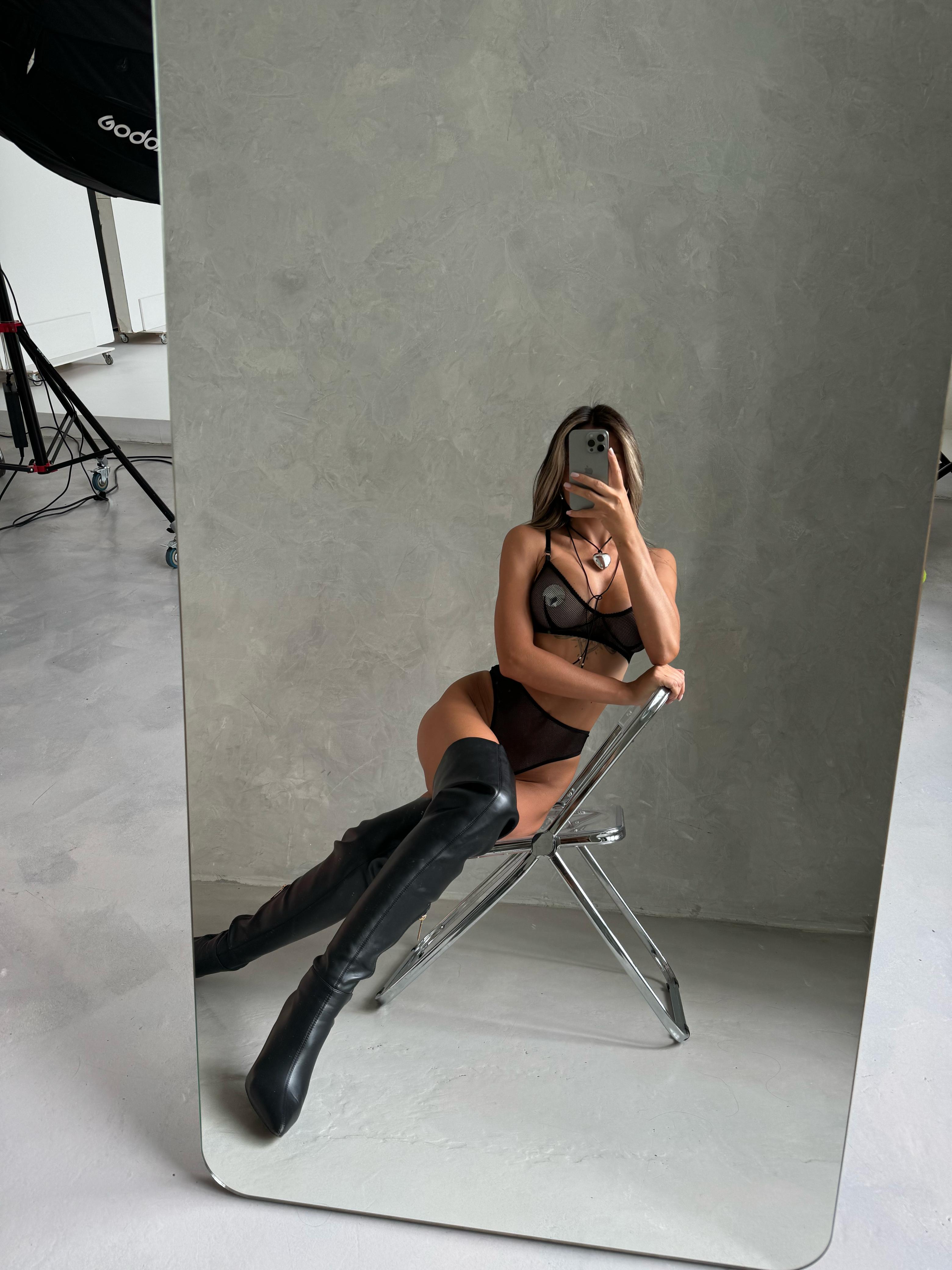 woman sitting and taking a selfie wearing a black Mesh Bra & Panty set