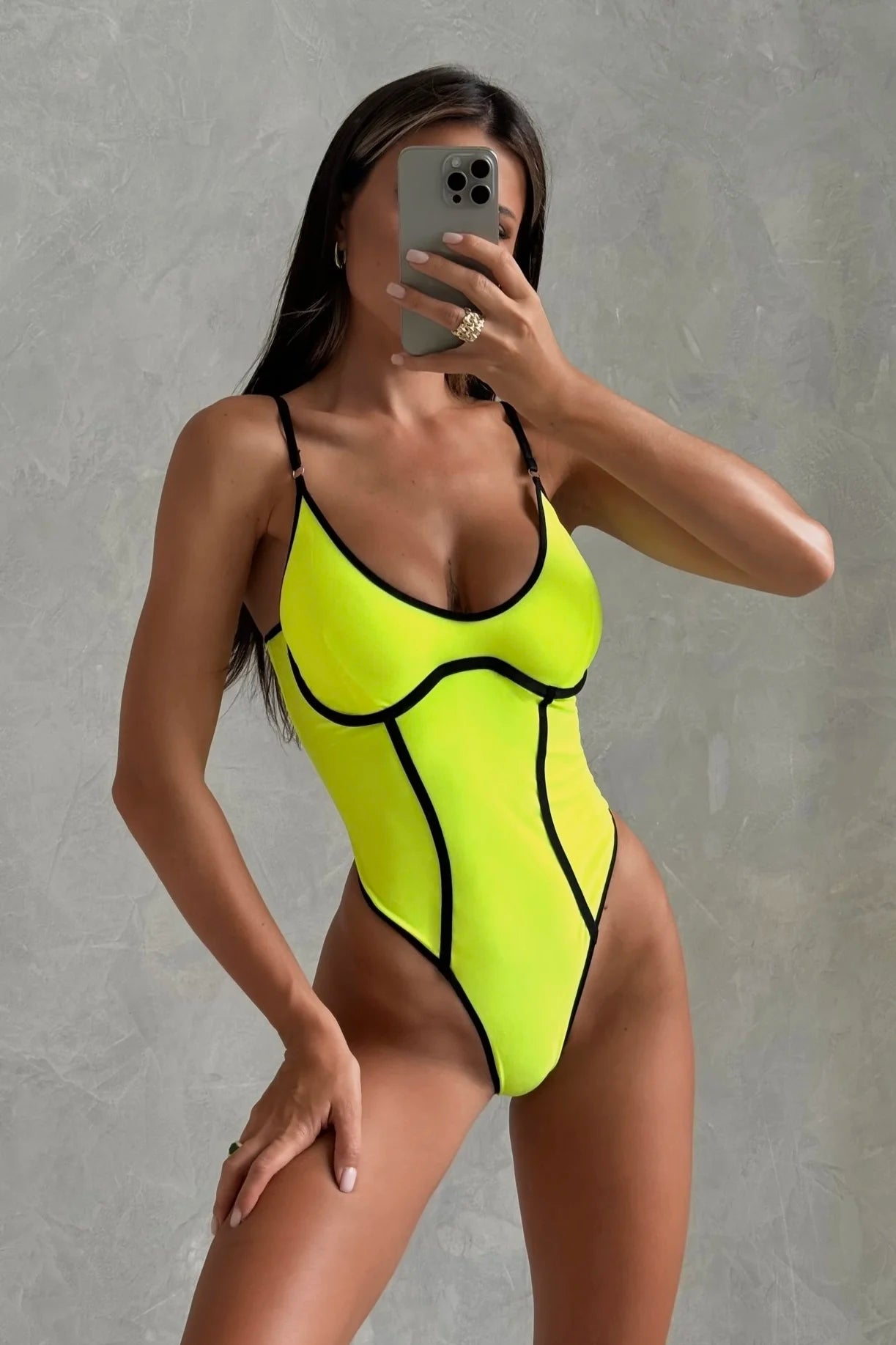 This image features a striking swimsuit in a vivid bay yellow color, with contrasting black detailing. The design includes a deep V-neckline and slim strap details on the shoulders, emphasizing a sleek and modern aesthetic.