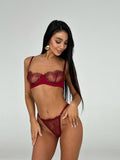 Woman wearing a red lace lingerie set against a plain background