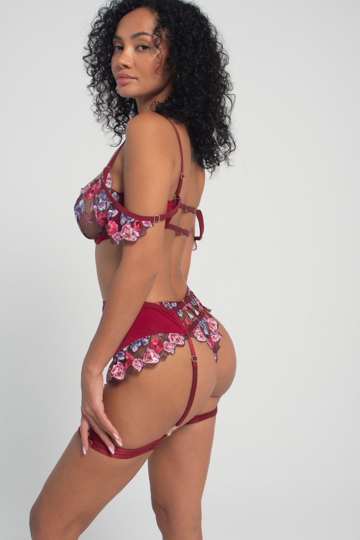 woman wearing a ruby coloured floral lingerie set with wings