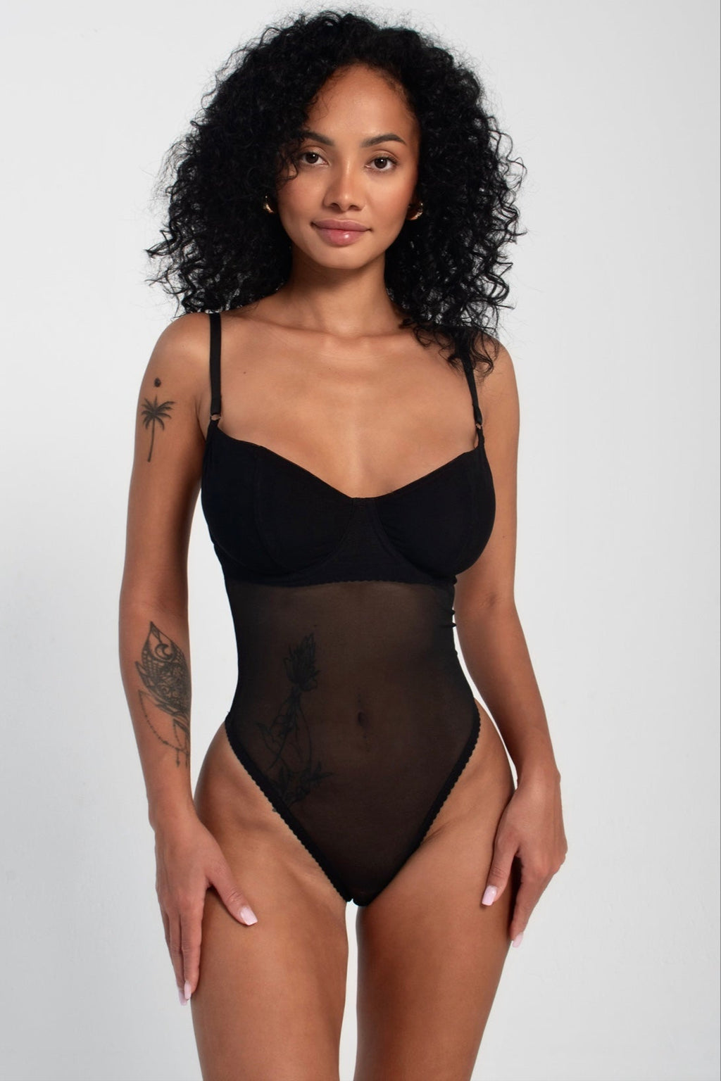 This image features a sleek, black bodysuit known as the NAPOLI model, designed to accentuate the waist and visually elongate the legs. Crafted from a blend of polyamide, elastane, and cotton, this garment promises both comfort and a flattering fit.