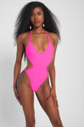 A model wearing a neon pink one-piece swimsuit with a deep V-neckline and minimal coverage.